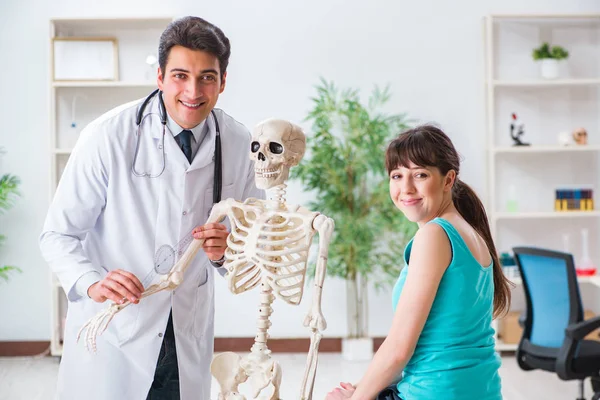 Medico che mostra il tipo di lesione sullo scheletro al paziente — Foto Stock