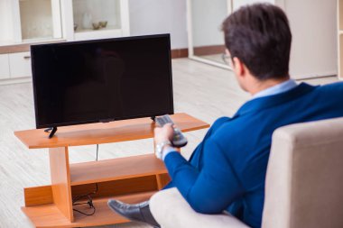 İş adamı ofiste televizyon izliyor.