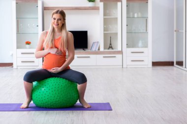 Evde doğum egzersizi yapmaya hazırlanan genç bir kadın.