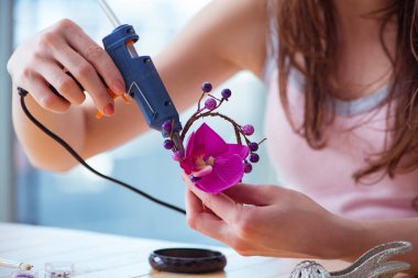 Kadın evde mücevher yapıyor.