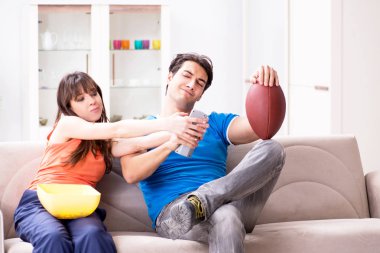 Adam karısıyla Amerikan futbolu seyrediyor.