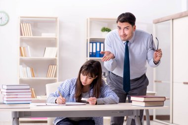 Erkek öğretim görevlisi bayan öğrenciye ders veriyor.