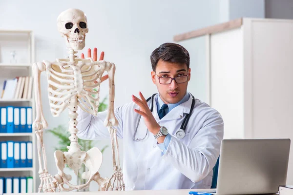 Yong médico masculino com esqueleto isolado em branco — Fotografia de Stock