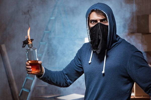 Мятежник с коктейлем Молотова в темной комнате