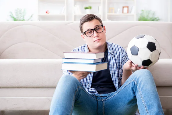 Joven estudiante tratando de equilibrar estudiar y jugar al fútbol — Foto de Stock