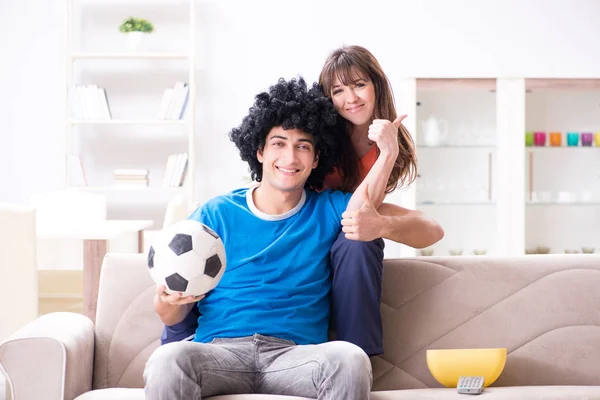 Mladý muž sleduje fotbal se svou ženou doma — Stock fotografie