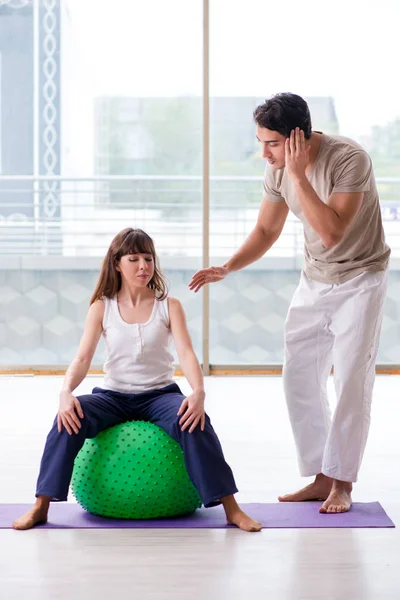 Treinador pessoal ajudando mulher no ginásio com bola de estabilidade — Fotografia de Stock