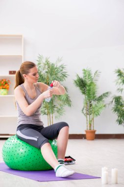 Spor salonunda denge topuyla egzersiz yapan genç bir kadın.