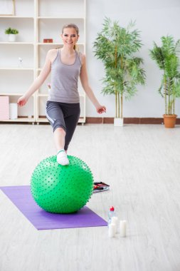 Spor salonunda denge topuyla egzersiz yapan genç bir kadın.