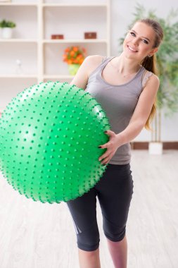 Spor salonunda denge topuyla egzersiz yapan genç bir kadın.