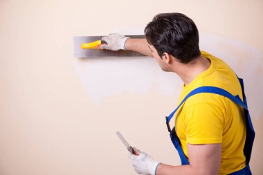 Duvara alçı yapıştıran genç müteahhit.