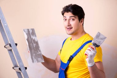 Duvara alçı yapıştıran genç müteahhit.