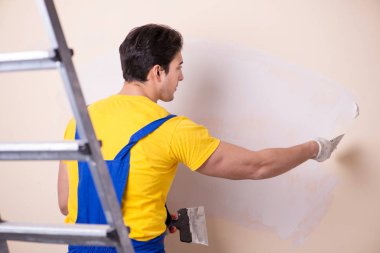 Duvara alçı yapıştıran genç müteahhit.