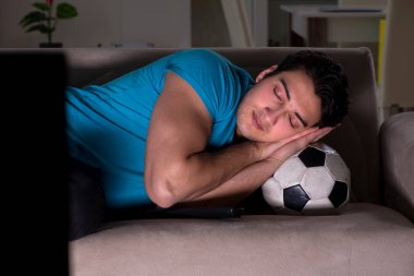 Genç adam gece geç saatlerde futbol seyrediyor.