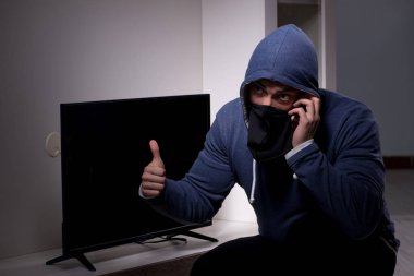Hırsız, apartmandan televizyon çalıyor.