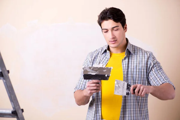 Young man applying plaster on wall at home — Stock Photo, Image