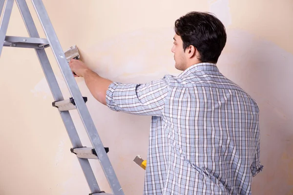 Hombre joven aplicando yeso en la pared en casa — Foto de Stock