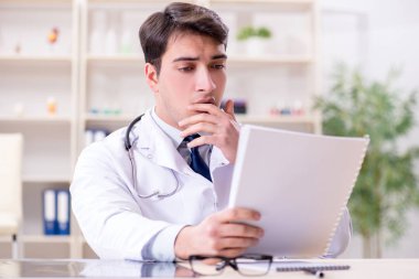 Genç doktor ofiste oturuyor.