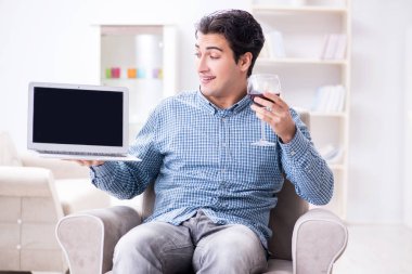 Genç adam evde şarap içiyor.