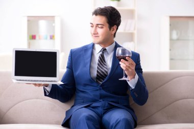 İş adamı evde oturmuş şarap içiyor.