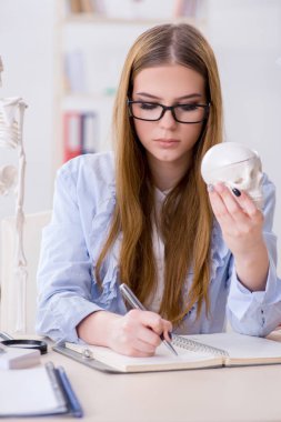 Öğrenci sınıfında oturuyor ve iskelet çalışıyor.