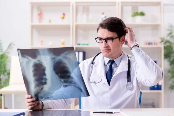 Médico joven mirando imágenes de rayos X en la clínica —  Fotos de Stock