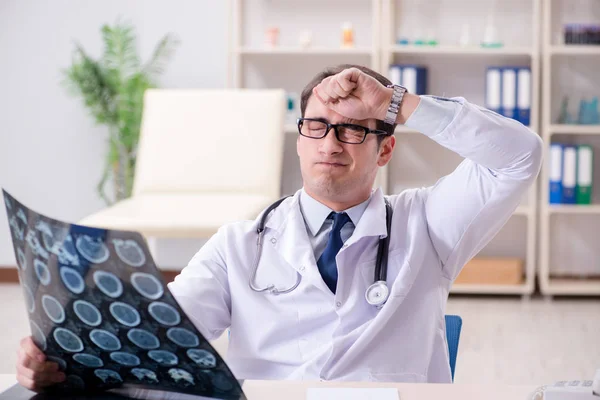 Junger Arzt schaut sich Röntgenbilder in Klinik an — Stockfoto