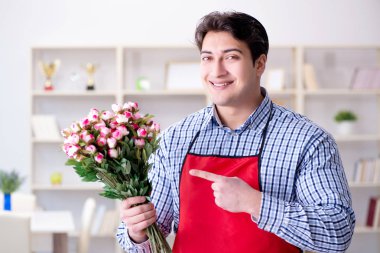 Çiçekçi asistanı bir demet çiçek veriyor.