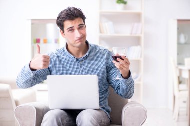 Genç adam evde şarap içiyor.