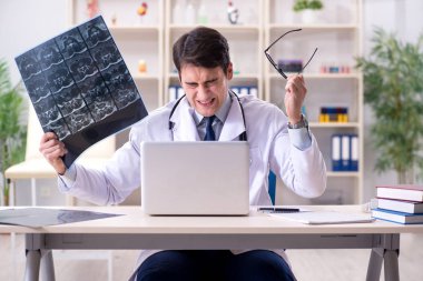 Genç doktor klinikteki röntgen görüntülerine bakıyor.