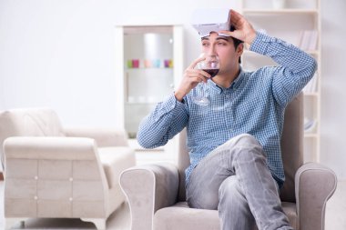 Genç adam evde şarap içiyor.