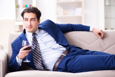 İş adamı evde oturmuş şarap içiyor.