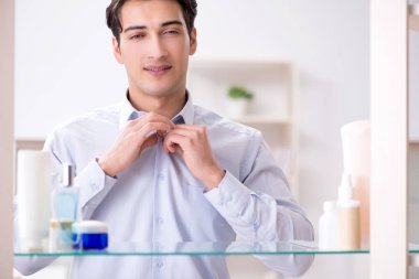 Adam banyoda çalışmak için giyiniyor.