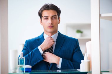 Adam banyoda çalışmak için giyiniyor.