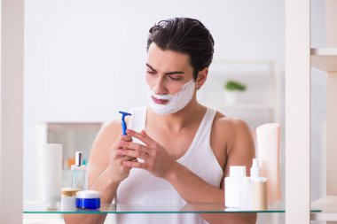 Genç yakışıklı adam sabah erkenden tıraş oluyor.