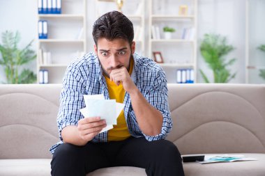 Ödeme yapması gereken faturalara kızgın bir adam.