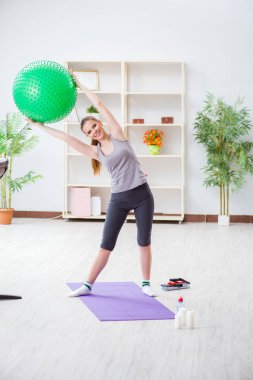 Spor salonunda denge topuyla egzersiz yapan genç bir kadın.