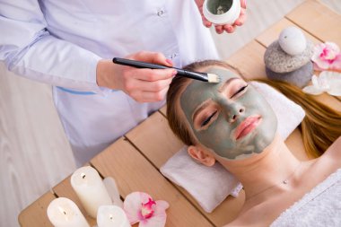 Yüz maskeli, spa sağlık konsepti olan genç bir kadın.