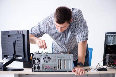 Genç teknisyen atölyede bilgisayar tamir ediyor.