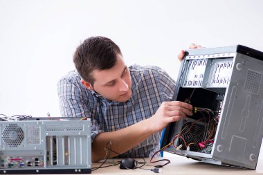Genç teknisyen atölyede bilgisayar tamir ediyor.