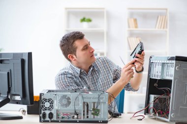 Genç teknisyen atölyede bilgisayar tamir ediyor.