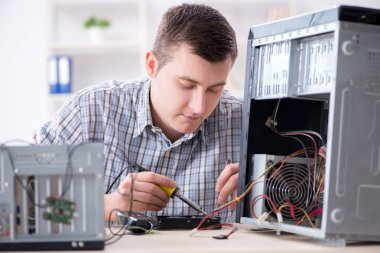 Genç teknisyen atölyede bilgisayar tamir ediyor.