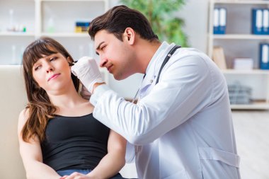 Doktor muayene sırasında hastaların kulaklarını kontrol ediyor.