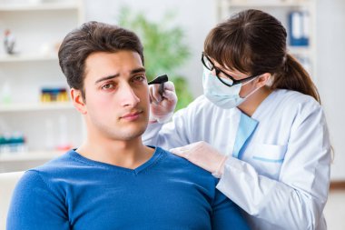 Doktor muayene sırasında hastaların kulaklarını kontrol ediyor.