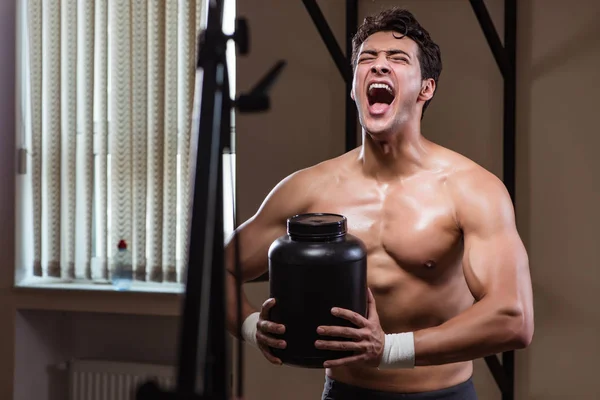 Homem com suplementos nutricionais no ginásio desportivo — Fotografia de Stock