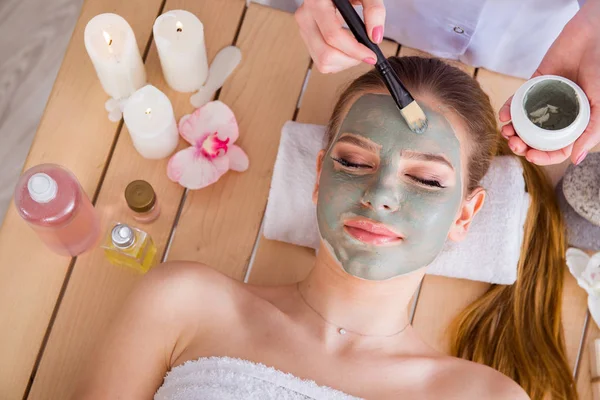 Mujer joven en concepto de salud spa con mascarilla facial — Foto de Stock