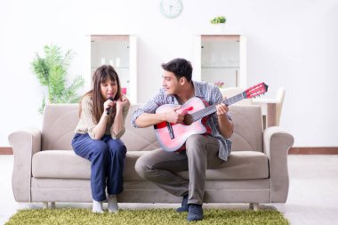 Genç bir aile evde şarkı söylüyor ve müzik çalıyor.