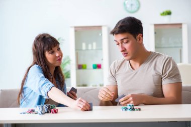 Genç bir aile evde kağıt oynuyor.