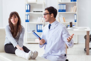 Kırık bacaklı bir hastayı muayene eden doktor.