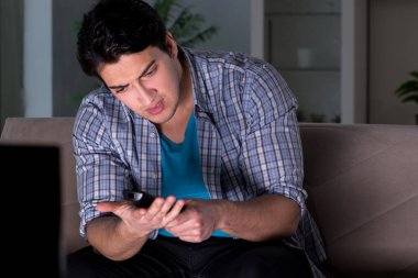 Genç adam gece geç saatte televizyon izliyor.